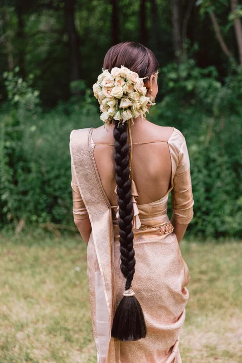 Long bridal braid with a white flower arrangement and pink saree