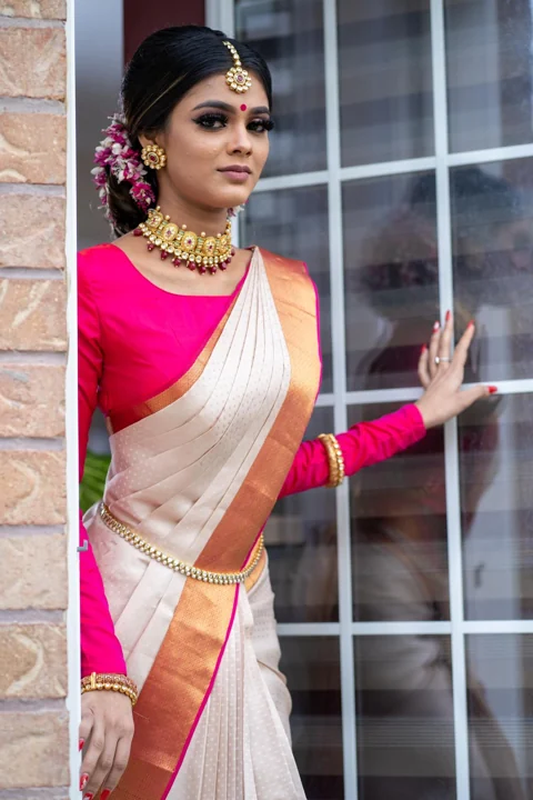 Traditional bridal makeup and floral hairstyle with an ivory and pink saree
