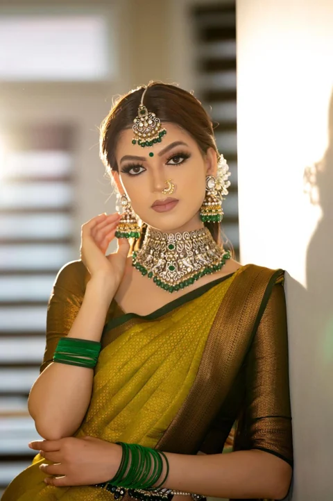 Olive and gold saree bridal look with emerald jewellery and refined makeup