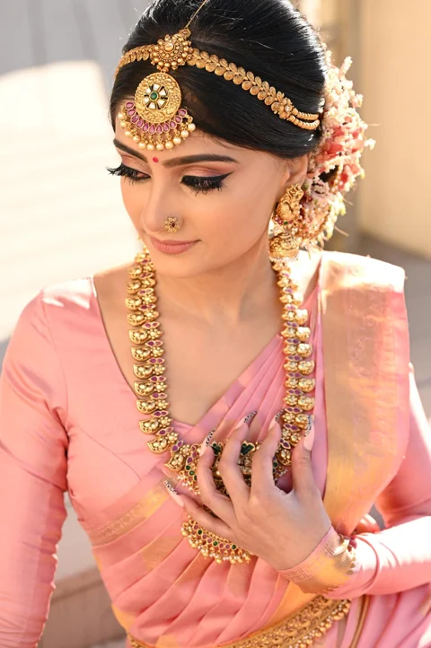 Pink silk saree with layered gold bridal jewellery and flower styling