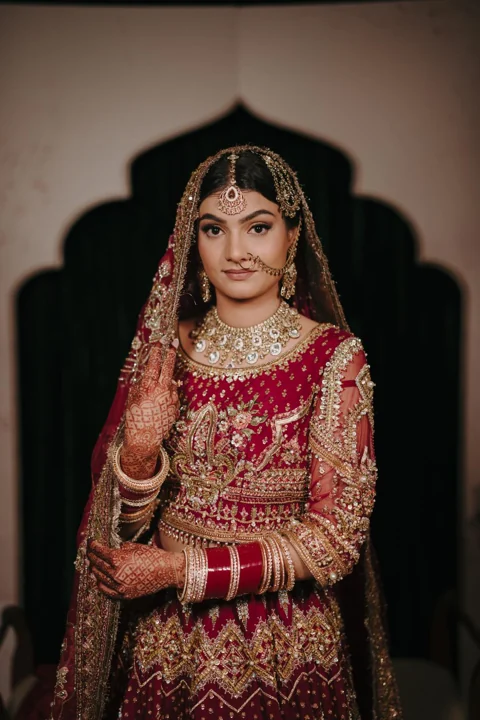 Traditional red bridal lehenga with gold jewellery and veil styling