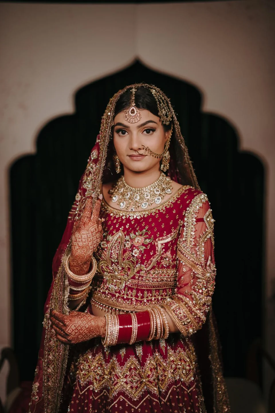 Red lehenga bridal look with gold jewellery and veil styling